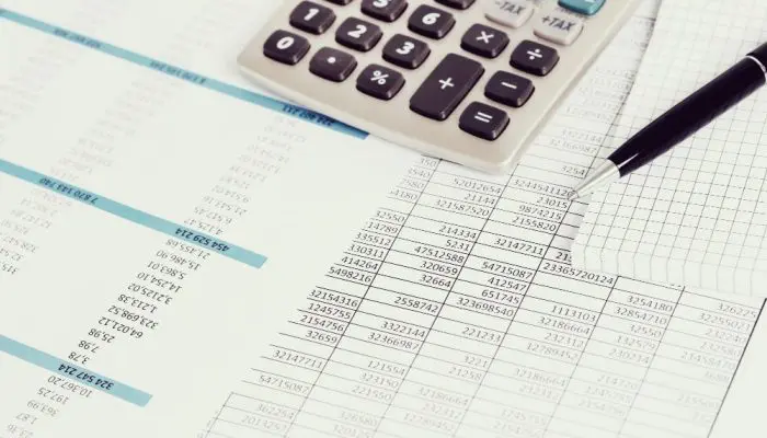 Bilde av en kalkulator og en penn på regnskapsdokumenter